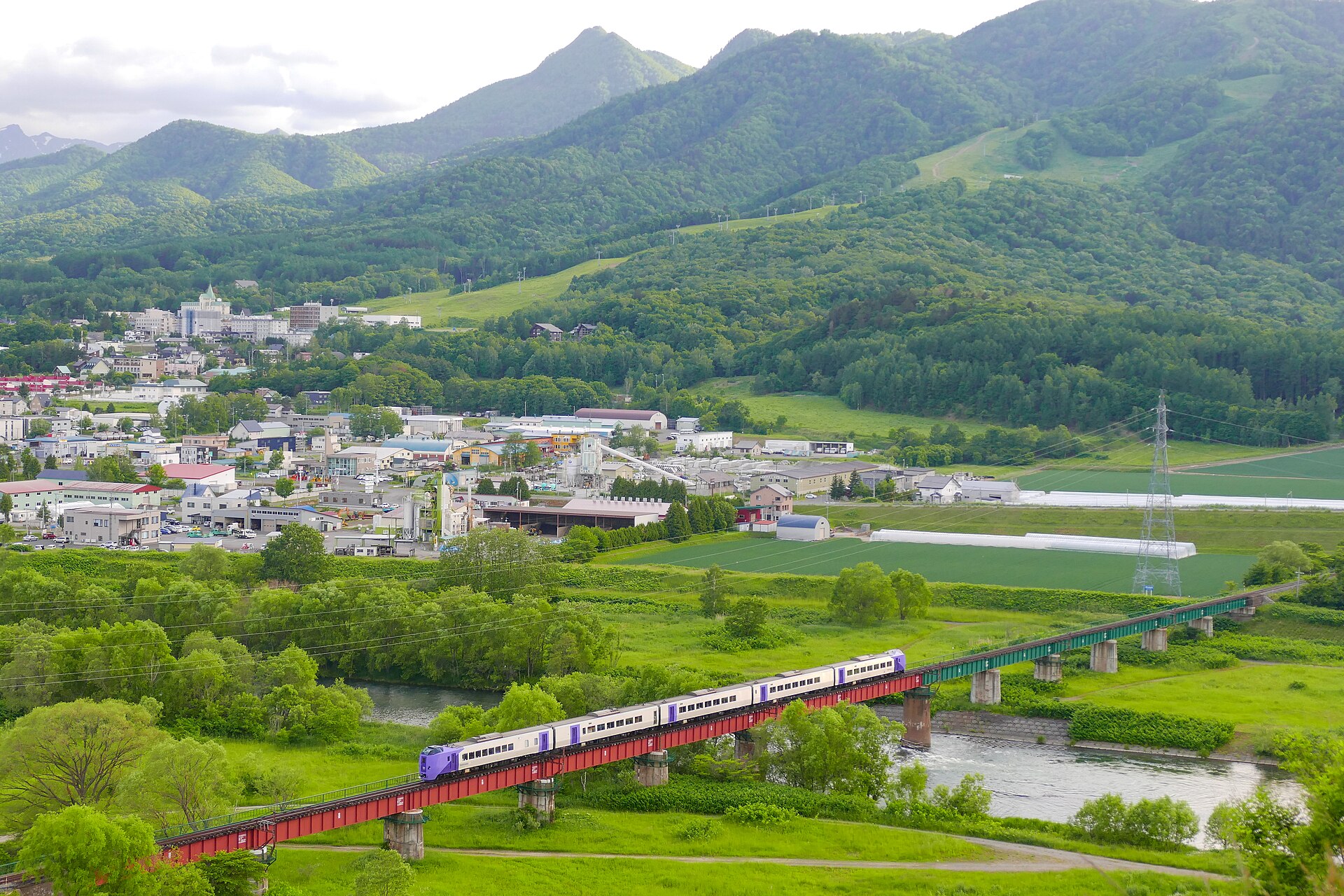 富良野市の空知川を鉄橋で渡る列車と市街地
