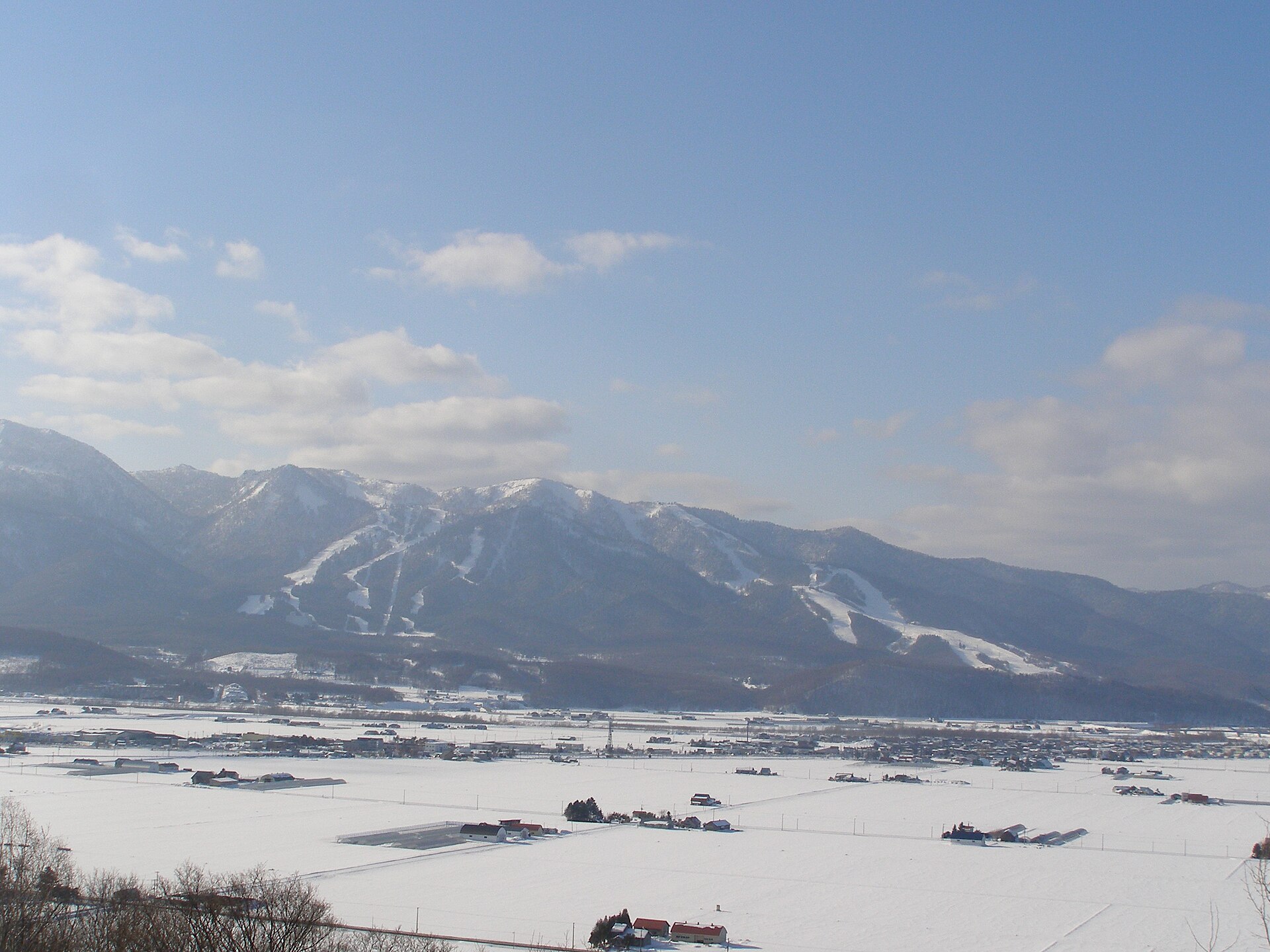 雪の富良野盆地の向こうに見えるスキー場のゲレンデ